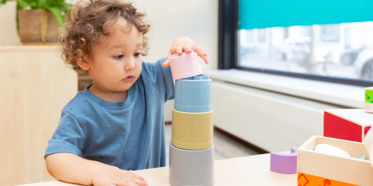 Kind stapelt blokjes op tafel van kinderdagverblijf.